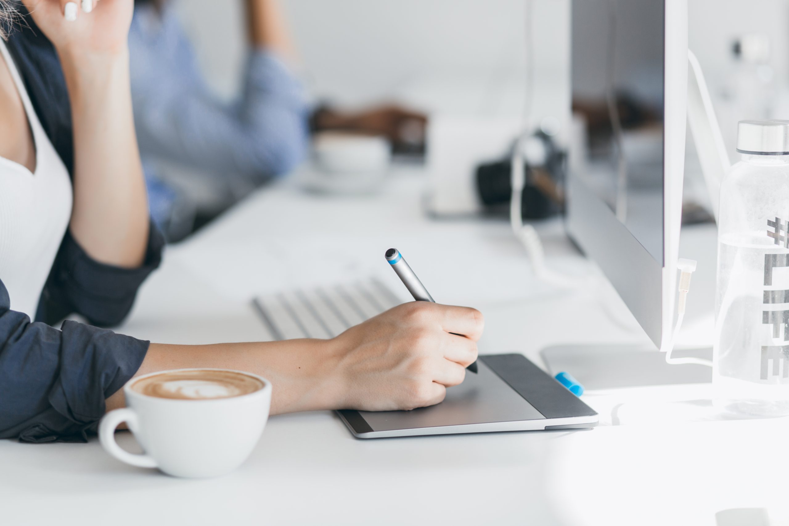 Close-up photo of female hand holding stylus on tablet. Indoor portrait of freelance web-developer working on project during coffee-break in office..